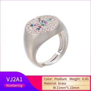 Dettaglio dell'anello regolabile in ottone con cristalli bianchi e motivo a croce colorata