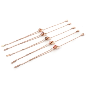 Détail de bracelets doubles anneaux en or rose avec zircons colorés et fermoir mousqueton