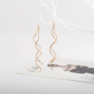 Macro shot of elegant rose gold spiral tassel earrings hanging on a white branch