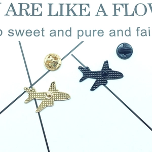 Golden and black airplane pins showing textured metallic back details and secure clasps