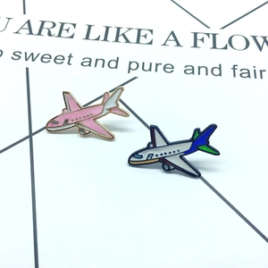 Detail view of pink glitter and blue enamel airplane pins on a white decorative card