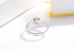 Detail of adjustable silver ring band with six-prong diamond setting on white background