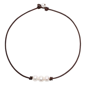 Vue détaillée de trois perles blanches sur un collier en cuir marron avec fermoir perle