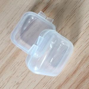 Two small clear plastic square storage boxes with lids on a wooden surface