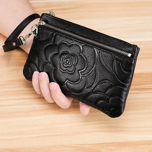 Close-up of black litchi leather coin purse with embossed floral pattern and wrist strap