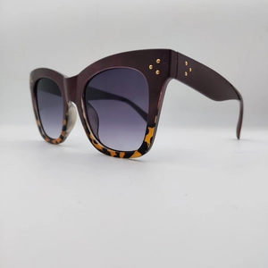Close-up of cat-eye sunglasses featuring leopard print frame and gold rivet details