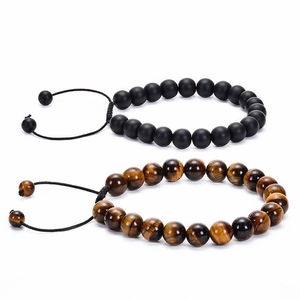 Macro detail of natural red tiger eye and matte black stone beads with braided cord