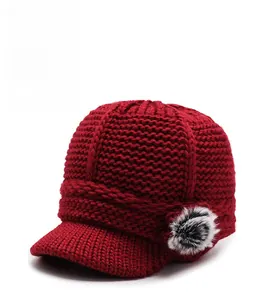 Detail of red cable-knit winter hat with fleece lining and faux fur pom-pom trim