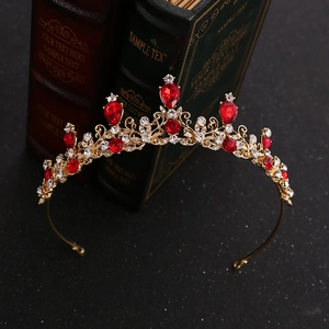 Dettaglio di corona dorata con cristalli rossi a goccia e design vintage traforato fine