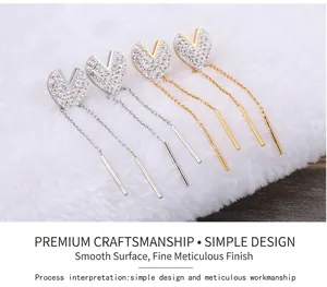 Detailed view of gold and silver heart-shaped tassel earrings with pavé zircon setting