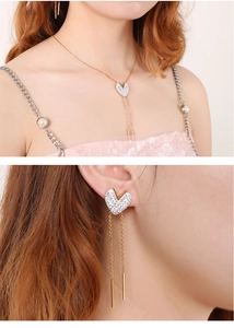 Detailed view of heart-shaped gold necklace and tassel earrings with white rhinestones