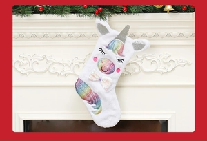 Detail view of plush unicorn Christmas stocking hanging on a white fireplace with decor