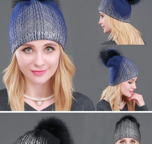 Detail showing two models wearing navy blue and black winter knit hats with fluffy pom-poms