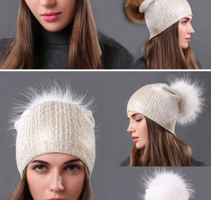 Close-up of knit beanie with metallic gold threads and large fluffy faux fur pompom