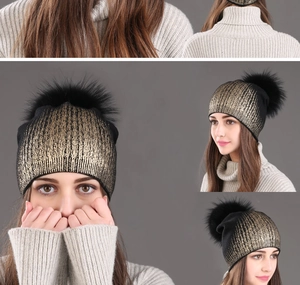 Detail of black winter knit beanie with gold metallic stripes and fluffy faux fur pompom