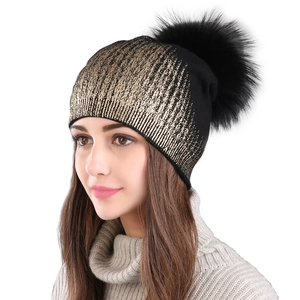 Women's black knit beanie with gold foil texture and a fluffy fur pompom detail