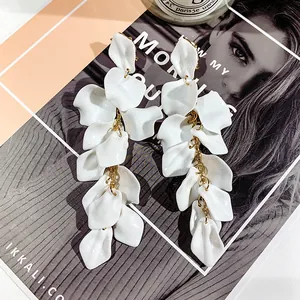 Detail of long cascading white resin flower petal earrings on a fashion magazine background