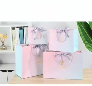 Detail of gradient gift bags with golden heart icons and elegant ribbon handles