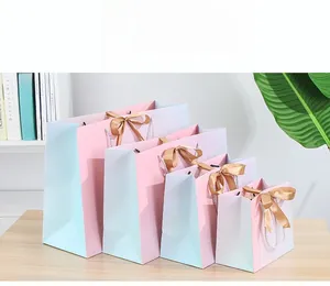 Set of five gradient gift bags with elegant gold satin bows and white woven handles