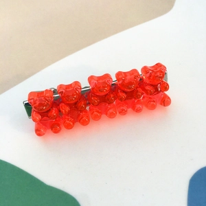 Detail view of five red resin gummy bears on a silver metal alligator hair clip