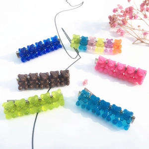 Flat lay of colorful gummy bear resin hair clips on metal duckbill clips with floral accents