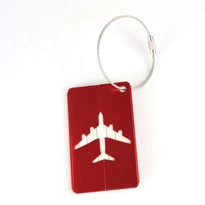 Macro view of red metal luggage tag featuring a hollow airplane design and steel cable loop