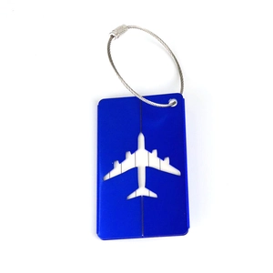 Close-up of blue metal luggage tag with airplane cutout and stainless steel wire loop