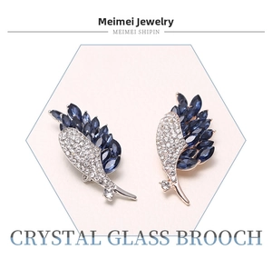 Detailed view of feather crystal brooches with blue marquise gems and pave setting