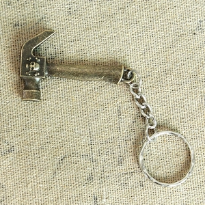 Detailed close-up of a vintage bronze hammer keychain with skull crossbone pattern on linen