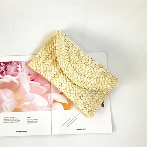 Detail of natural corn husk woven clutch bag placed on a summer fashion magazine