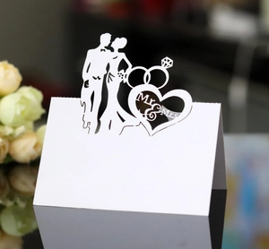 Close-up of laser-cut Mr & Mrs wedding place card with bride groom and rings detail