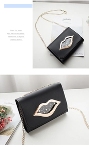Close-up of stylish black leather bag featuring a gold lip-shaped metal clasp and chain