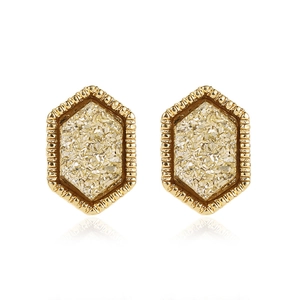 Macro detail of hexagonal gold earrings featuring glittering crushed stones and starry texture