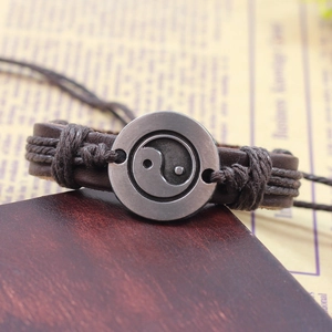 Vintage multilayer brown leather bracelet with Tai Chi Yin Yang metal charm on wood