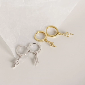 Detail of lightning bolt earrings in gold and silver finish with micro-inlaid rhinestones