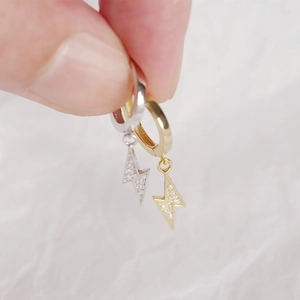 Macro shot of gold and silver lightning bolt earrings with micro-set zircons on s925 silver