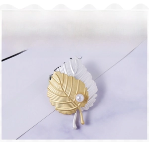 Detail of two-tone matte gold and silver leaf brooch with a central round white pearl
