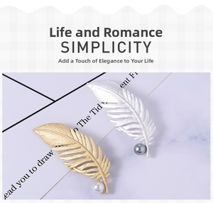 Detail of matte gold and silver feather brooches with elegant pearl accents