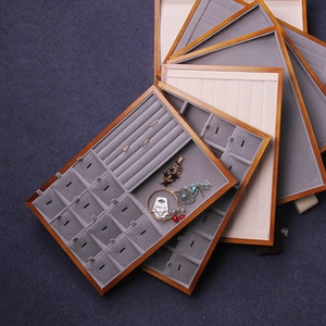 Close-up of wooden jewelry display tray with grey velvet compartments for watches and rings