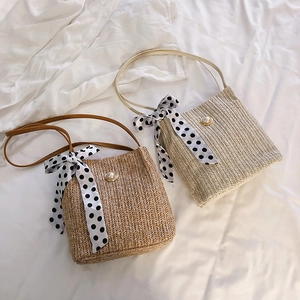 Detail of woven straw shell shoulder bags with pearl clasp and polka dot scarf bow