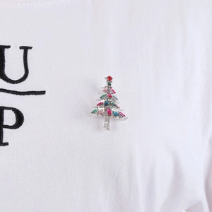 Detailed view of a vintage crystal Christmas tree brooch pinned on a white t-shirt