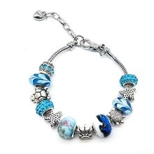Macro detail of silver snake chain bracelet with blue sea turtle and starfish charms