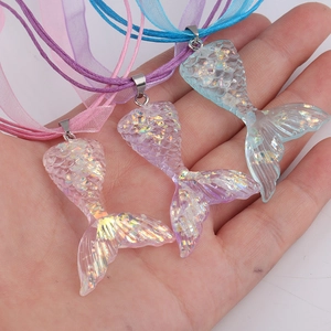 Close-up of three iridescent mermaid tail pendants in pink, purple, and blue colors