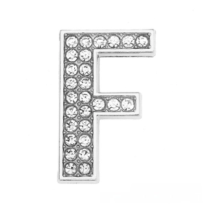 Macro detail of silver-toned metal letter F charm encrusted with sparkling rhinestones