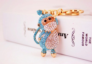 Macro shot of gold monkey keychain with blue crystals on white background