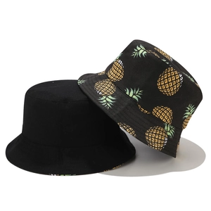 Détail d'un chapeau bob réversible avec imprimé ananas jaune et design noir minimaliste