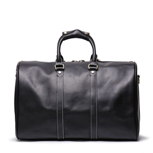 Macro shot of black leather travel bag showing detailed white stitching and metal hardware