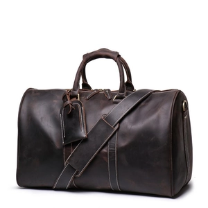 Detail view of vintage dark brown leather travel bag with luggage tag and shoulder strap