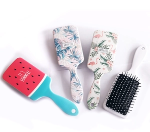 Flat lay of colorful cartoon square hairbrushes with fruit and tropical leaf patterns