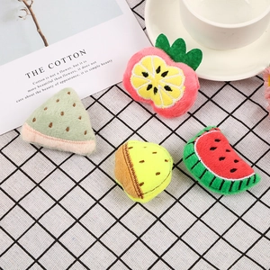 Plush cartoon fruit brooches including strawberry and watermelon on a checkered cloth